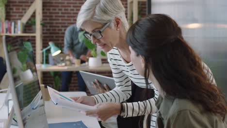 professional business women brainstorming using research data graphs looking at computer screen collaborating in modern office workspace background