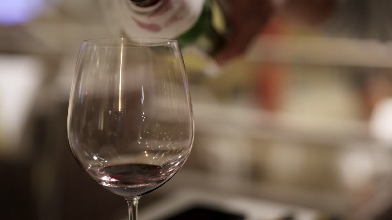 Una sequenza che mostra vino rosso versato in un bicchiere, evidenziando l'eleganza e la precisione della mescita