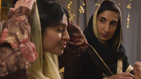 muslim mother and daughter eating around table at home celebrating eid