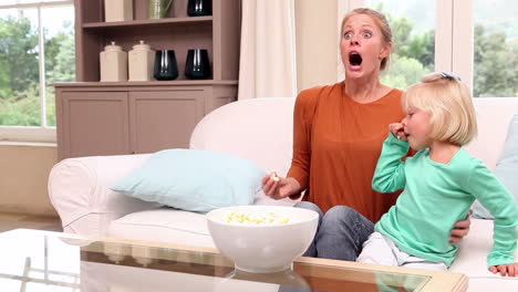 cute little girl watching tv with her mother