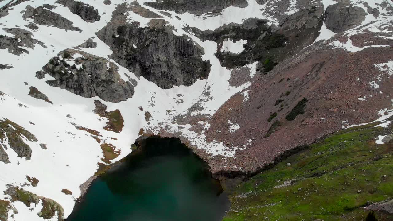 toma aérea de dolly hacia atrás del lago entre altas montañas cubiertas de nieve