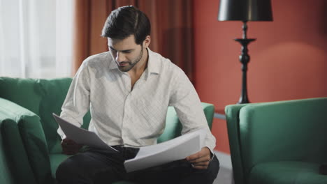 Focused-businessman-reading-documents-at-hotel.-Confident-man-checking-papers