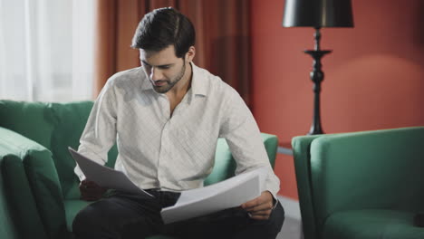 focused businessman reading documents at hotel. confident man checking papers