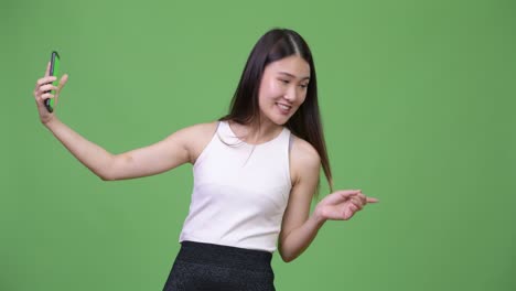 젊은 아름다운 아시아 사업가 여성이 전화를 보여주고 있습니다.