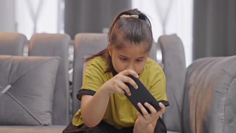 Competitive-Indian-kid-girl-playing-online-games-on-smartphone