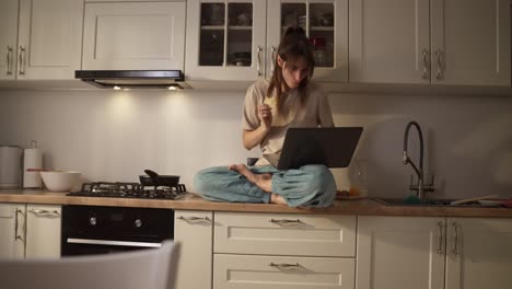 mujer trabajando y comiendo almuerzo en casa en la cocina