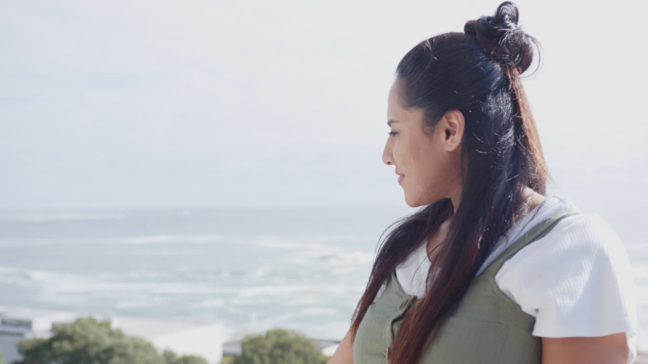 Enjoying peaceful spa retreat, mature asian woman relaxing by ocean, on balcony, copy space