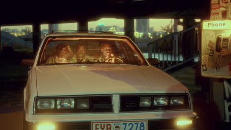 three black men chatting in car parked under city overpass at dusk