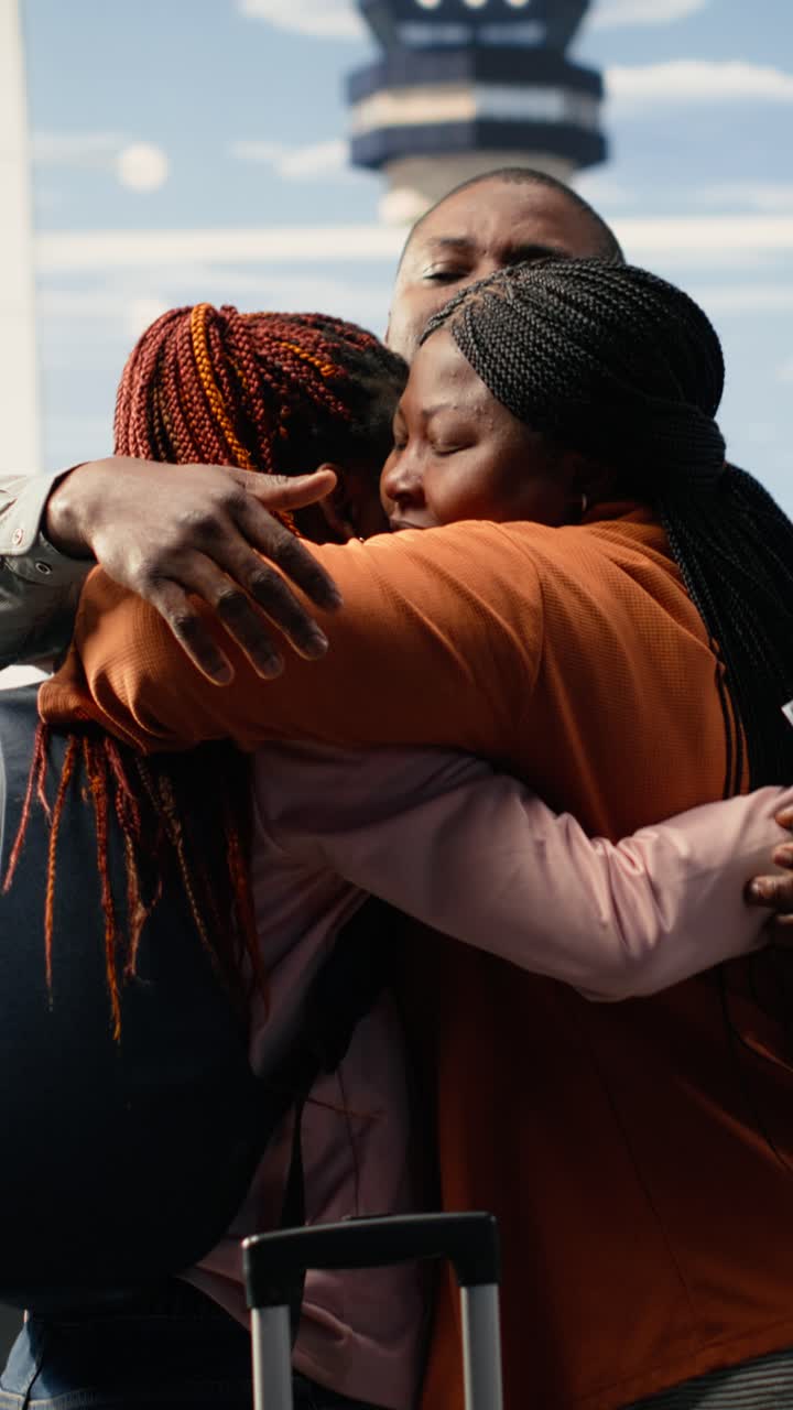 Felice famiglia africana che si abbraccia all'aeroporto durante un ricongiungimento