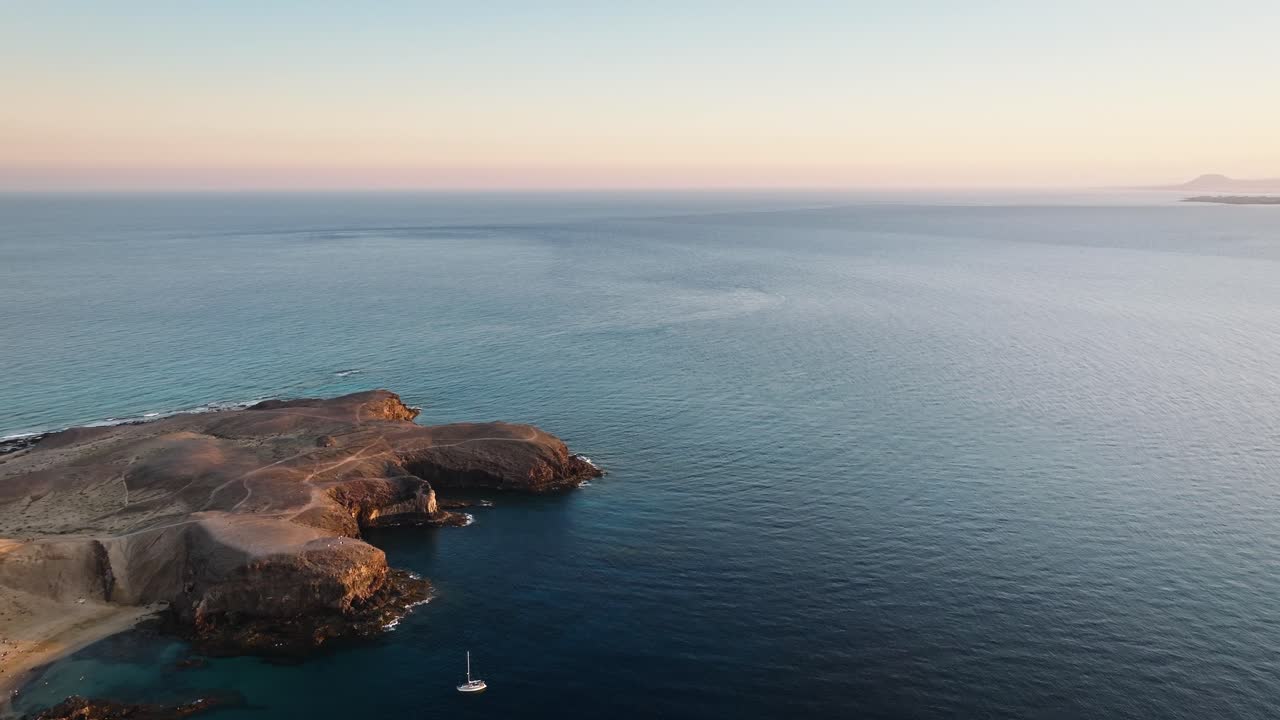 Stunning Drone Flight Over Lanzarote's Playa Mujeres with Sailboats and Fuerteventura in the Background During Beautiful Sunset