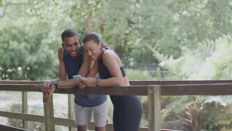 two fit athletes doing a high five on a bridge