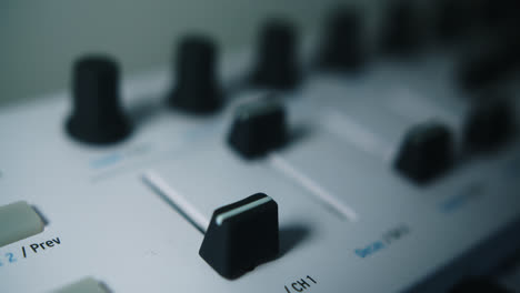 amazing slow motion, close-up, spotlight lit shot of a young latin musician's hand raising the fade of a midi piano keyboard in his home studio in his darkened room.