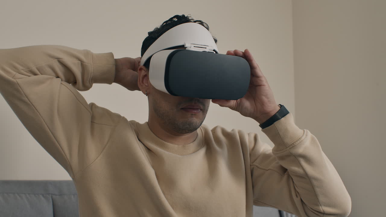 Man adjusts virtual reality headset, preparing for immersive experience at home