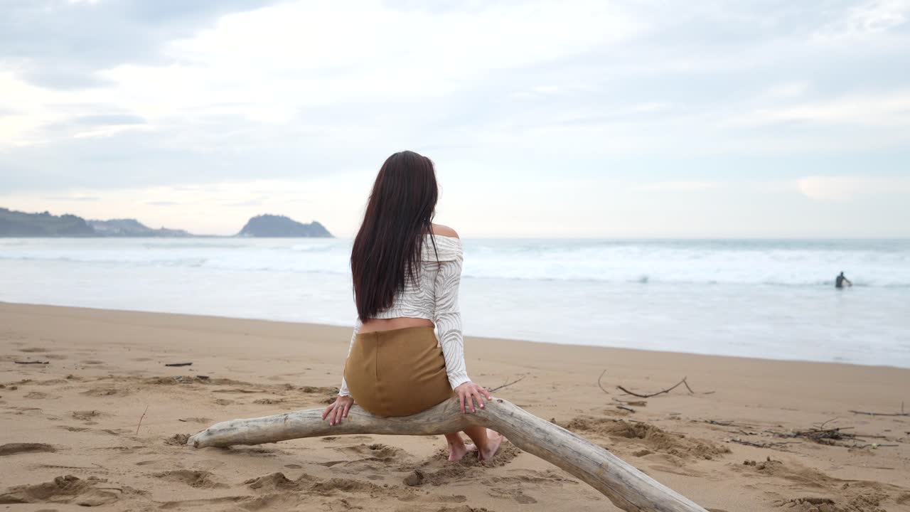 Woman sitting on a log at the beach