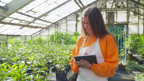 woman gardener taking notes in greenhouse