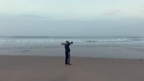 static view of man in black with portable piano strolling on the beach