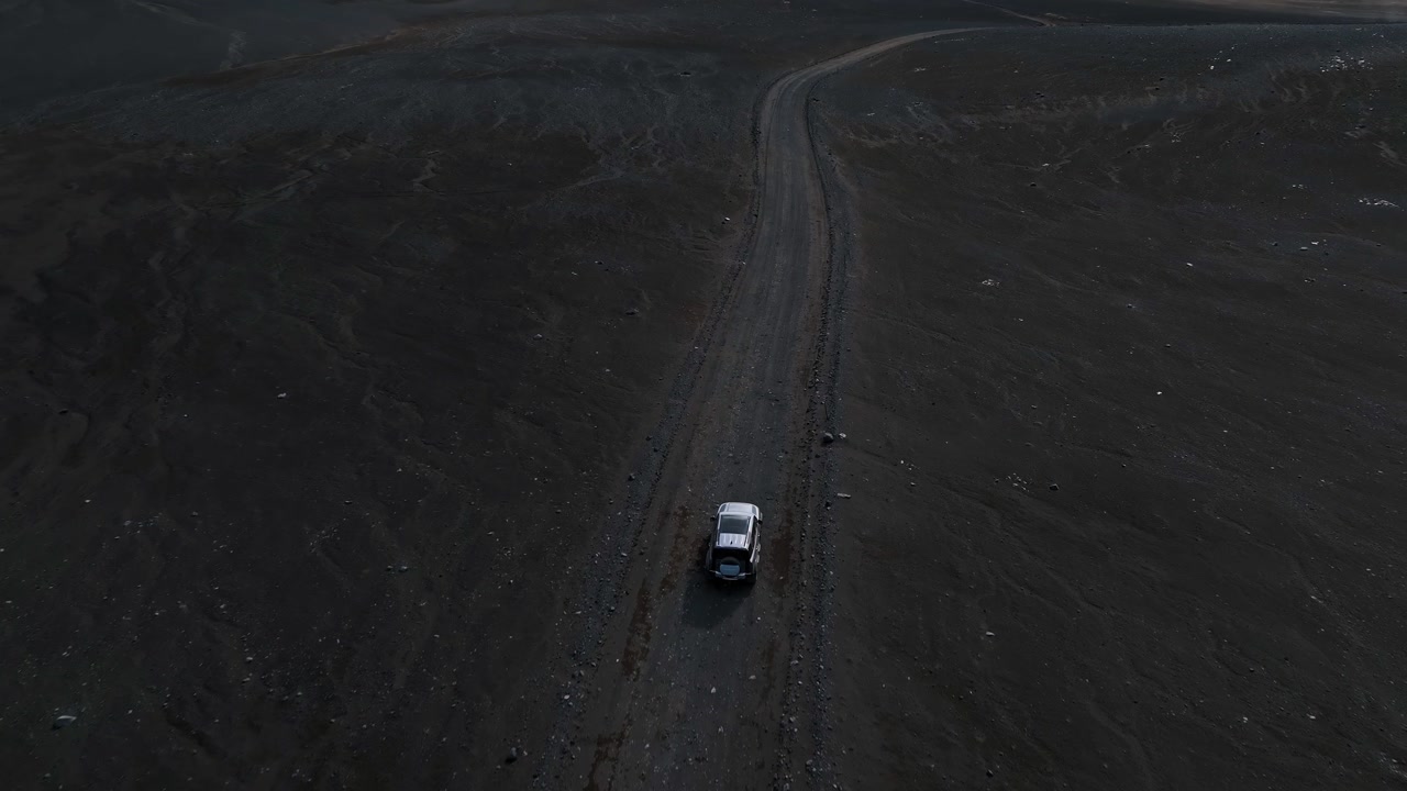 SUV car driving through volcanic sand and rugged hills in Iceland travel off road trip.
