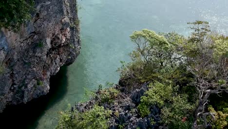 drone footage of longtail boat navigating around islands of thailand with the limestone rock formations sticking out of the water and the ocean in background-1