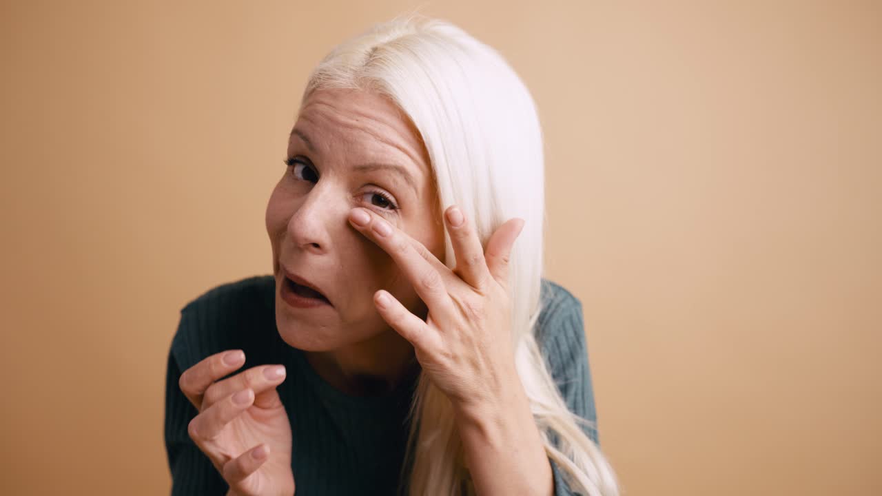 Gelukkige blonde vrouw lacht en raakt haar gezicht aan