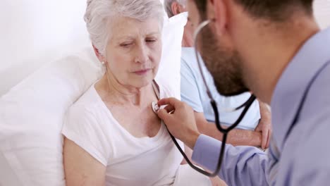 male nurse using stethoscope on senior woman