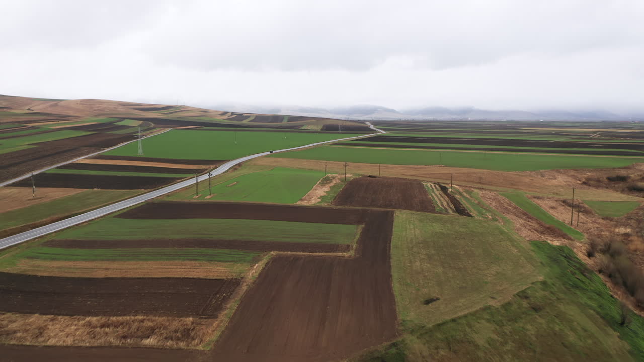 Cars drive through farmland in Sancraieni, Romania. Aerial dolly forward