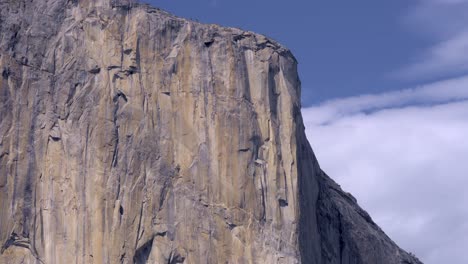 tight 4k telephoto shot highlights el capitan’s sheer granite face as clouds glide behind it in yosemite national park. ideal b-roll for travel, nature, geology or inspirational edits