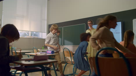 Students-learning-at-elementary-school.-Female-teacher-standing-at-blackboard