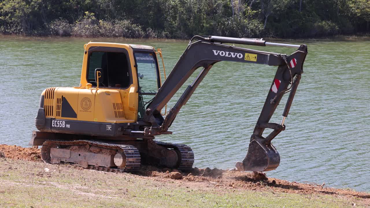 secuencia de una excavadora excavando cerca de un lago