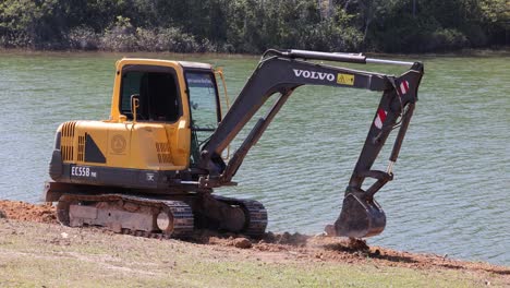 sequence of an excavator digging near a lake