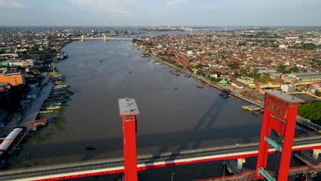 Cityscape-of-Palembang-on-sunny-day-with-red-color-bridge-of-Ampera,-aerial-view