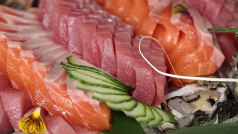a colorful display of sliced tuna, salmon, shrimp, and oysters with cucumber and floral garnishes.