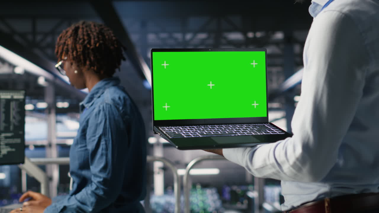 Close up of data center admins on industrial platform using green screen laptop