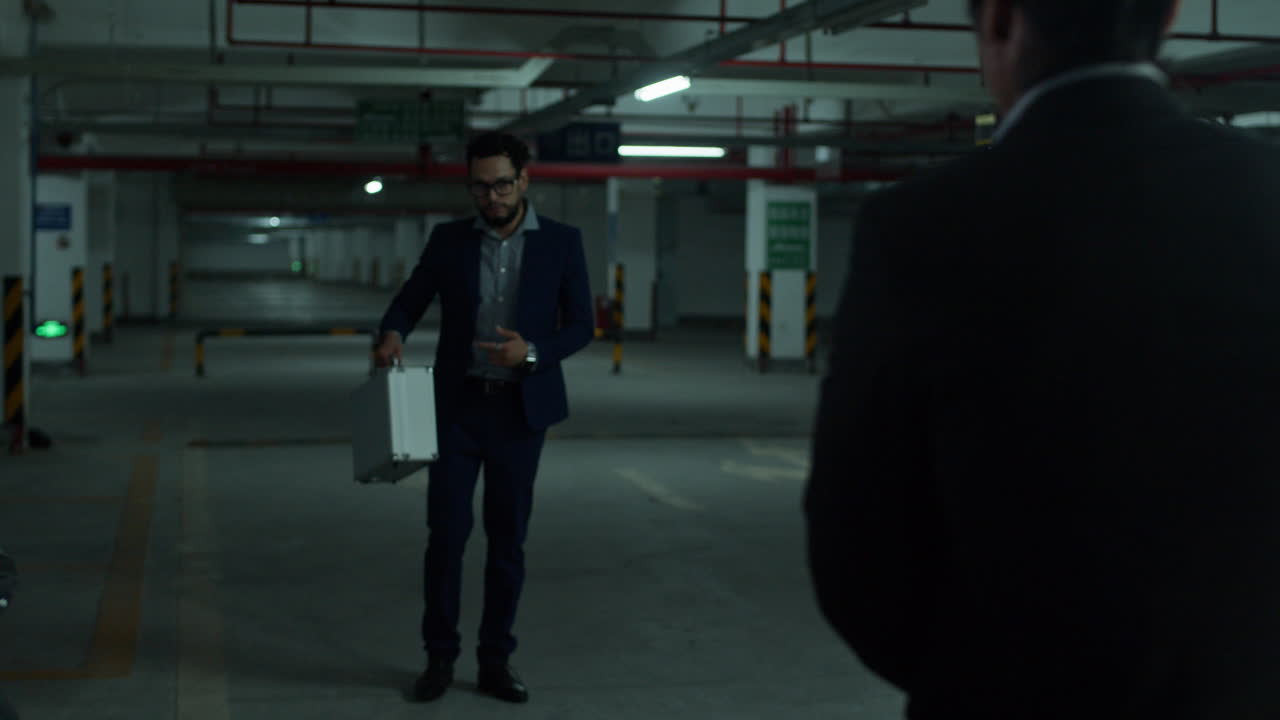 Businessmen Exchange Briefcase in Underground Parking Garage