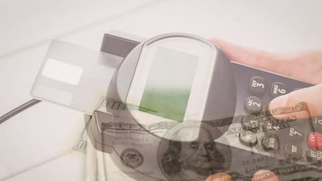 Animation-of-dollar-banknotes-falling-over-hand-of-caucasian-man-holding-payment-terminal