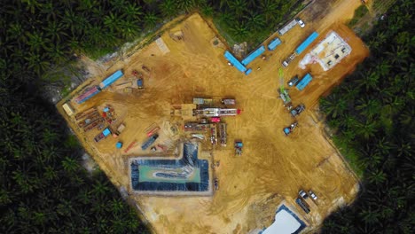imágenes cinematográficas de drones de la estructura del equipo de la plataforma de perforación en tierra para la exploración y explotación de petróleo en medio de la jungla rodeada de palmeras durante la puesta de sol y el alto precio del petróleo