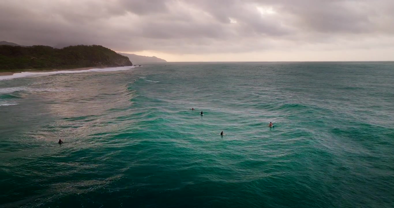 Surfare väntar på havsvågor utanför Los Naranjos strand i Tayrona, Colombia. Flygfoto med drönare, utrymme för text.