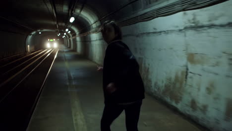 person running from approaching train in a dark subway tunnel