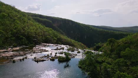 el agua brillante que cae en cascada sobre las rocas en una piscina serena, rodeada de vegetación exuberante y acantilados dramáticos, crea un oasis tranquilo en el parque nacional chapada dos veadeiros, brasil.