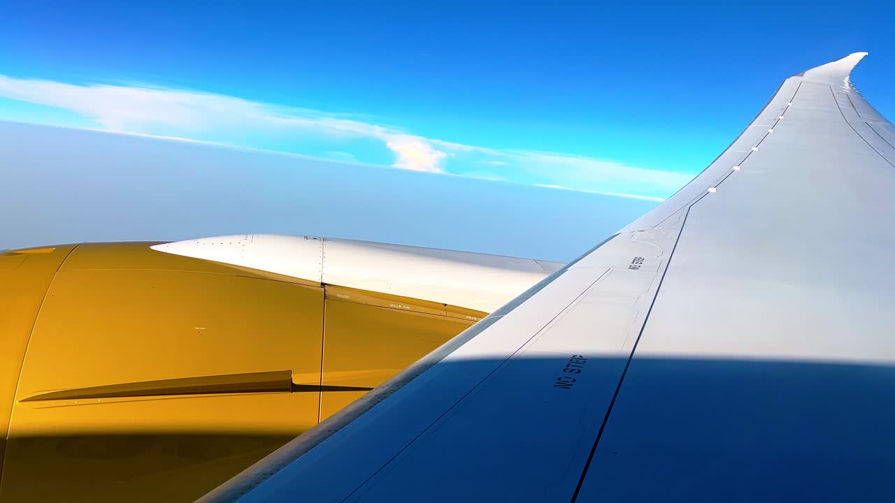 Striking view from an airplane window featuring a golden jet engine, sleek wing, and vivid blue sky, perfect for travel, aviation, and adventure visuals