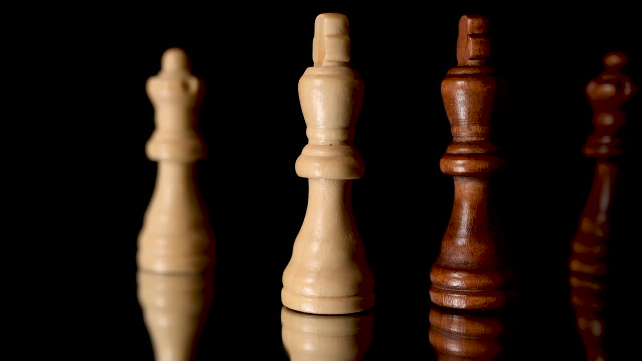 Brown and whit king, and brown and white queen, chess figures standing against each oter