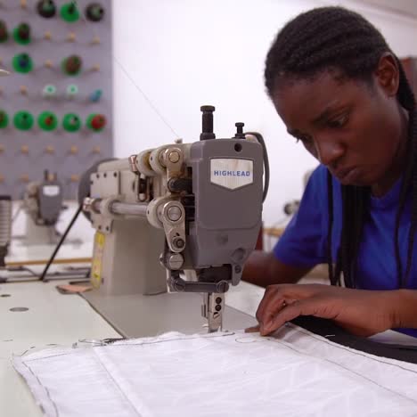 a woman worker sews a garment by hand in a sweatshop in zambia africa