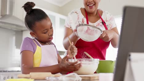 Happy-unaltered-african-american-mother-and-daughter-baking-in-kitchen,-in-slow-motion