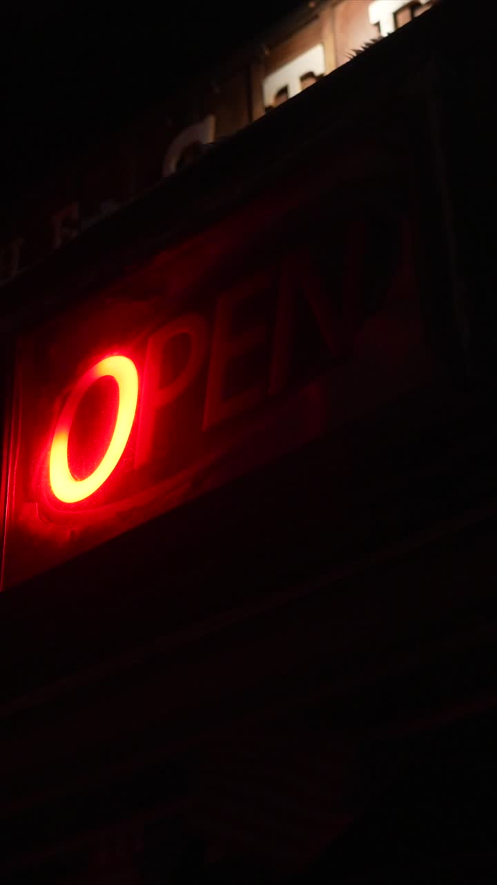 Cartel de neón vibrante y parpadeante de 'Abierto' por la noche