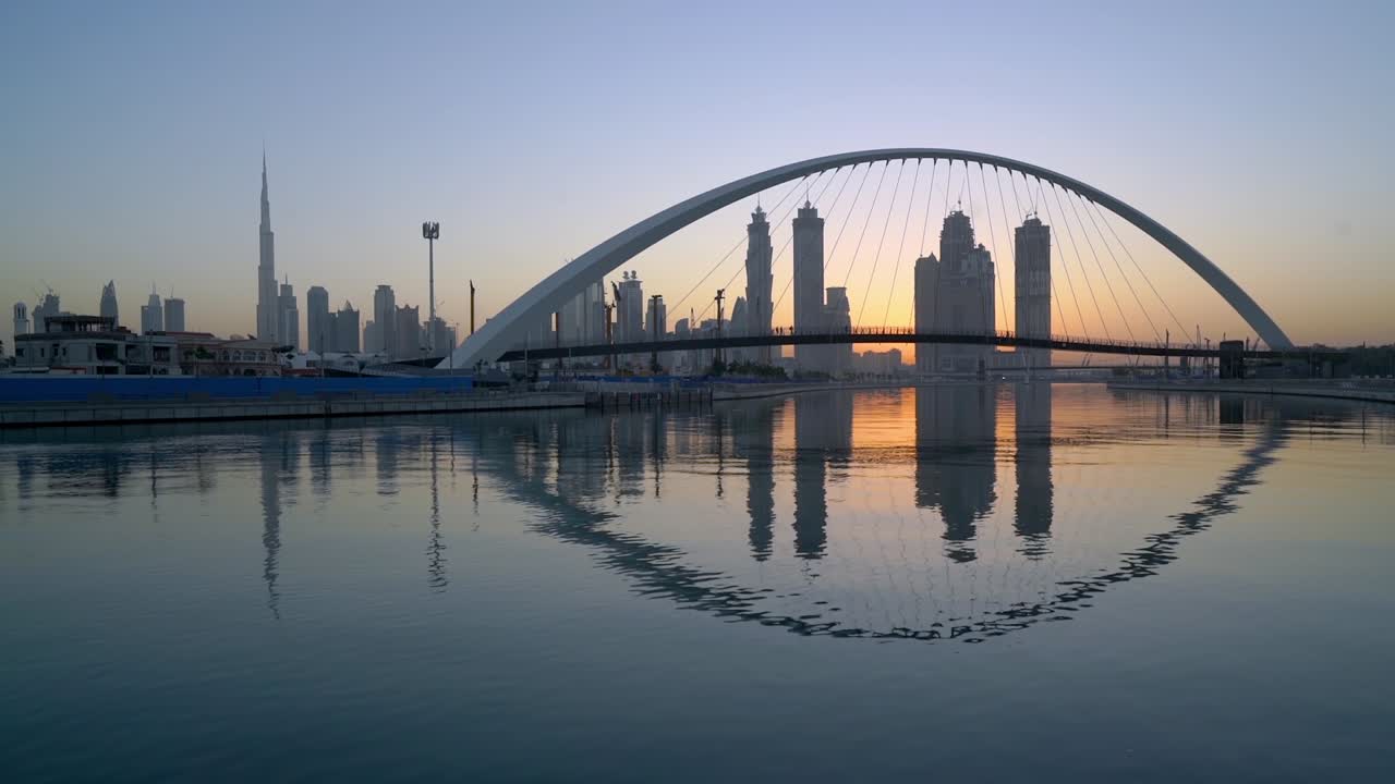 Dubai Canal - Dubai Water Canal Bridge Reflected In The Water With Downtown Skyline And Burj Khalifa On The Background At Sunset
