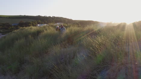 Drohnenaufnahme-Eines-älteren-Paares,-Das-Im-Winterlichen-Strandurlaub-über-Dünen-Läuft