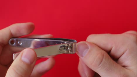 White-hands-fingers-nail-cutting-top-down-closeup,-red-background,-static