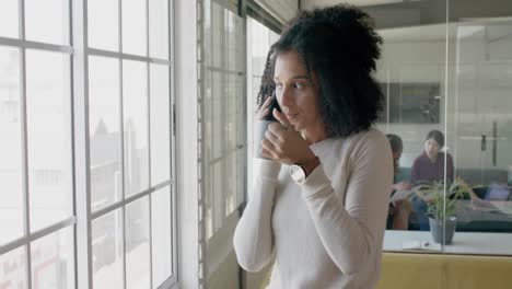 Happy-biracial-casual-businesswoman-talking-on-smartphone-in-creative-office,-slow-motion