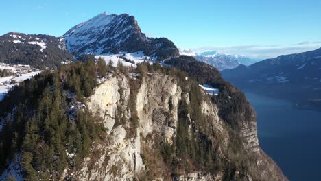 Toma-Aérea-Hacia-Adelante-De-La-Plataforma-De-Observación-Cubierta-De-Nieve-En-La-Cima-De-La-Montaña-Contra-El-Cielo-Azul