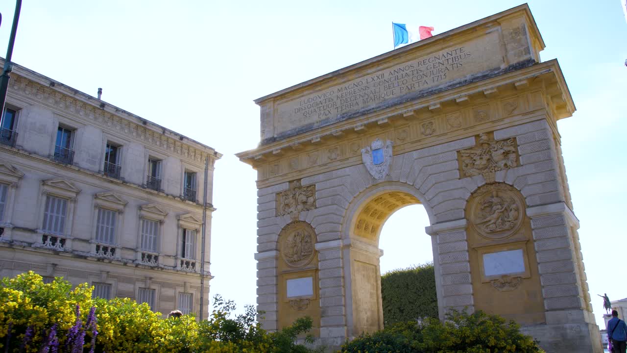 el arco triunfal de montpellier con los rayos del sol y la bandera francesa que ondea en su parte superior