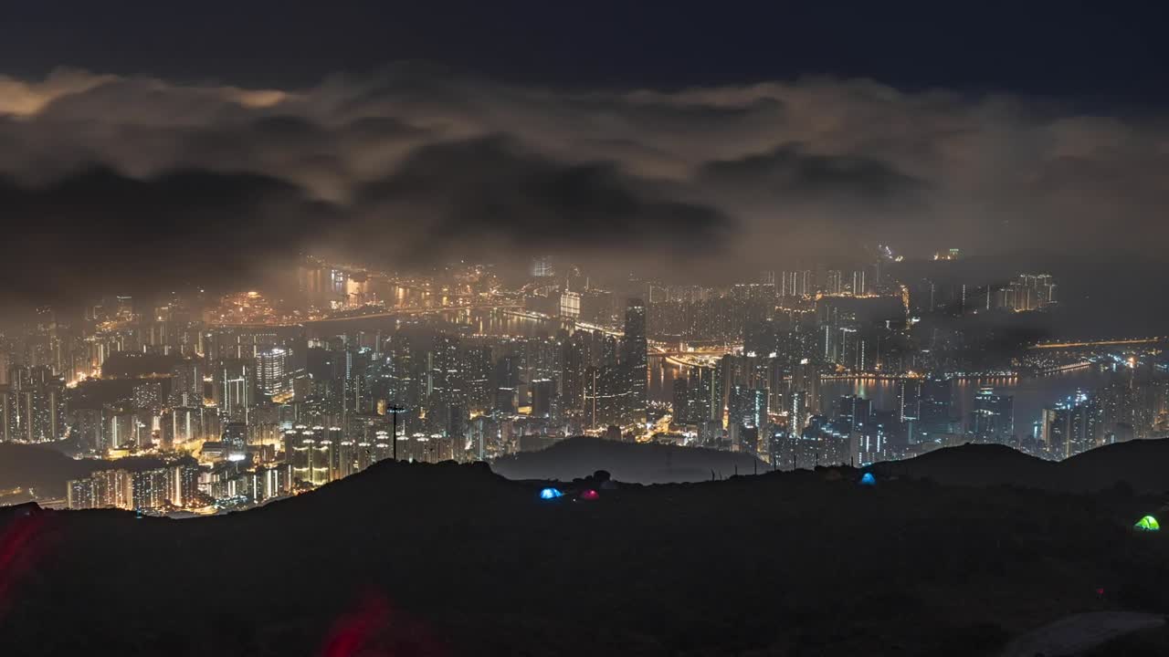 Night timelapse with grey transparent clouds flying on dark sky over city lights, cinematic background in Tai Mo Shan, Hong Kong